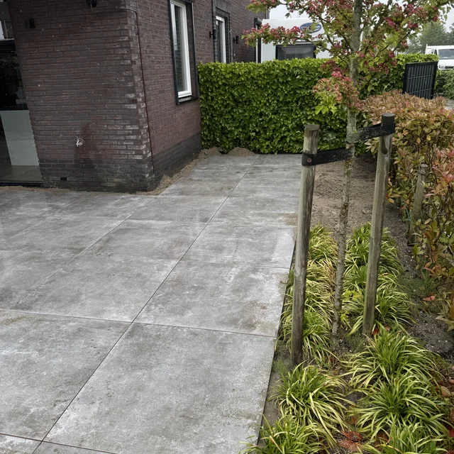 Zijpad van keramische tegels langs de gevel, met beplanting en kantopsluiting