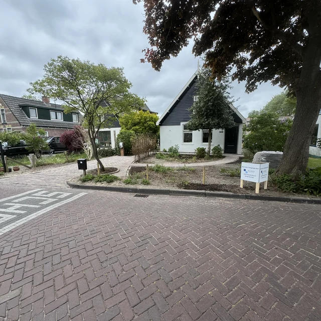 Overzicht van de voortuin vanaf de straat, oprit en trottoir in gebakken klinkers